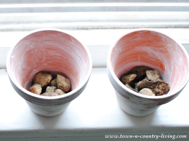 Adding stones to garden pots to provide drainage for plants.