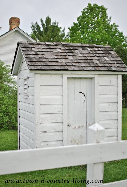 Shabby white outhouse at Pioneer Sholes School