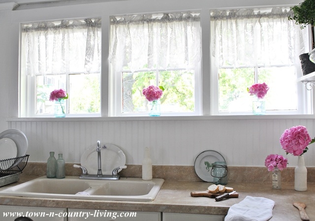 Lace valances in country kitchen windows via Town and Country Living
