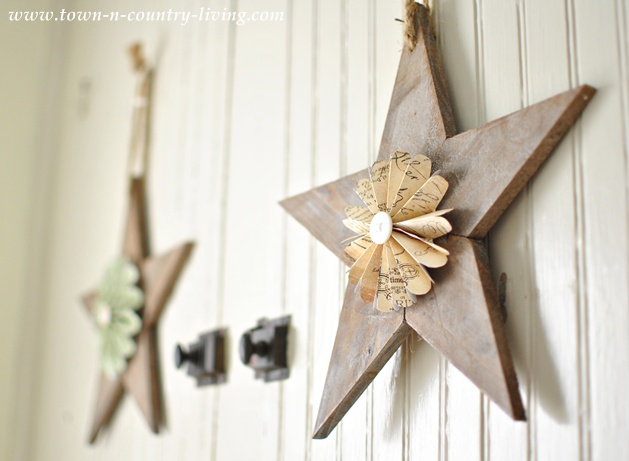 Wooden stars with paper fans hanging on a farmhouse hutch via Town and Country Living