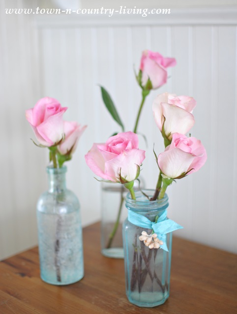 Single stem pink roses in vintage aqua bottles