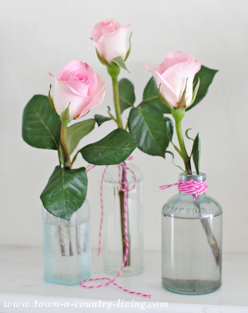 Trio of single stem roses in vintage bottles