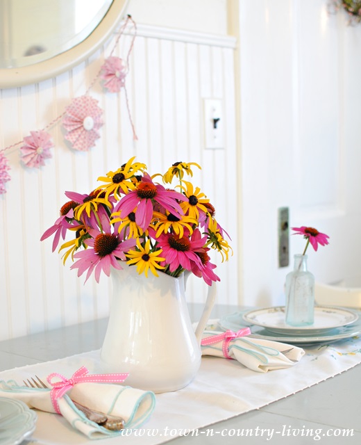 Coneflowers and Rudbeckia in a white ironstone pitcher make a simple centerpiece for a summer table setting.